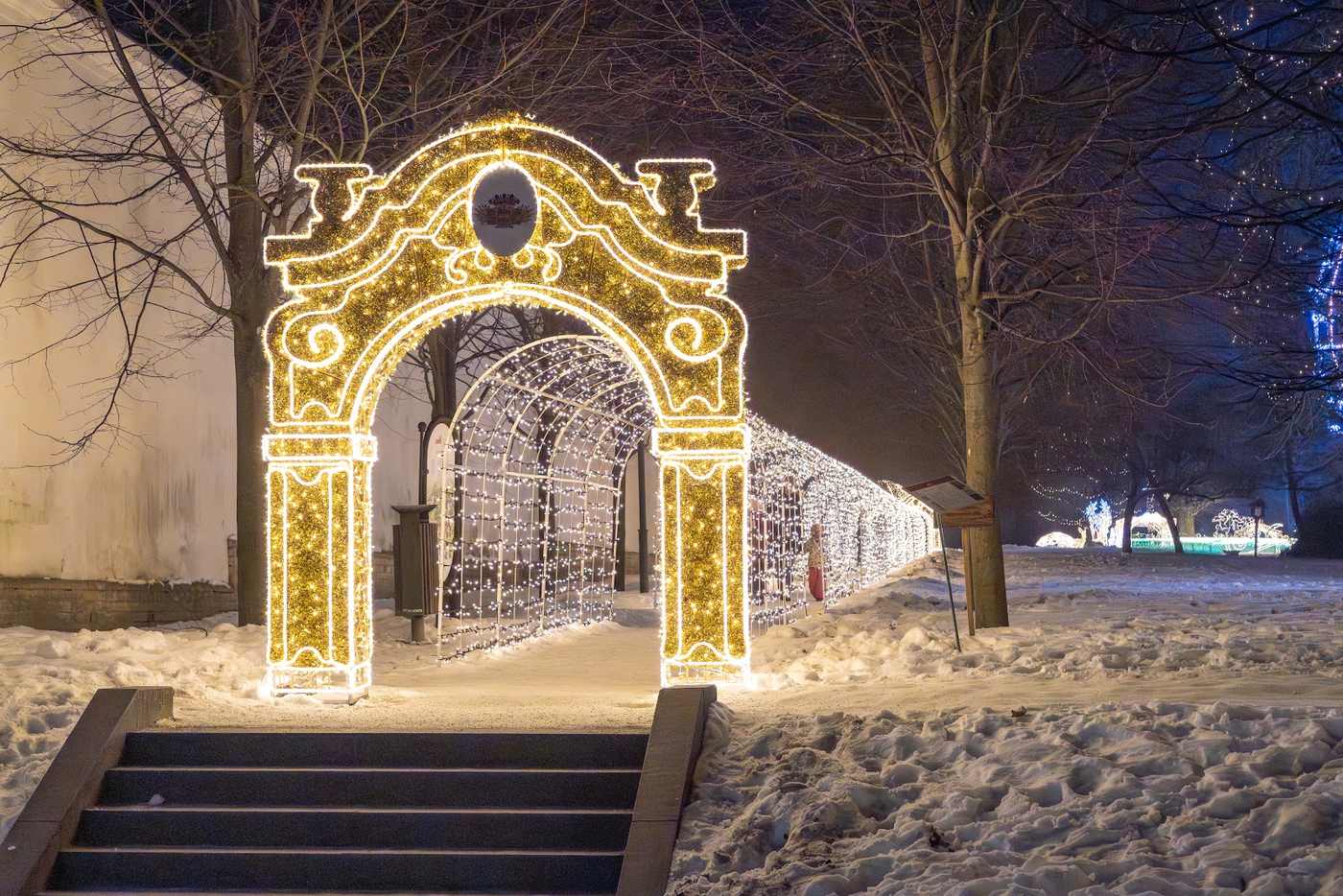 A baroque triumphal arch outlined in warm light at the top of a flight of stone steps