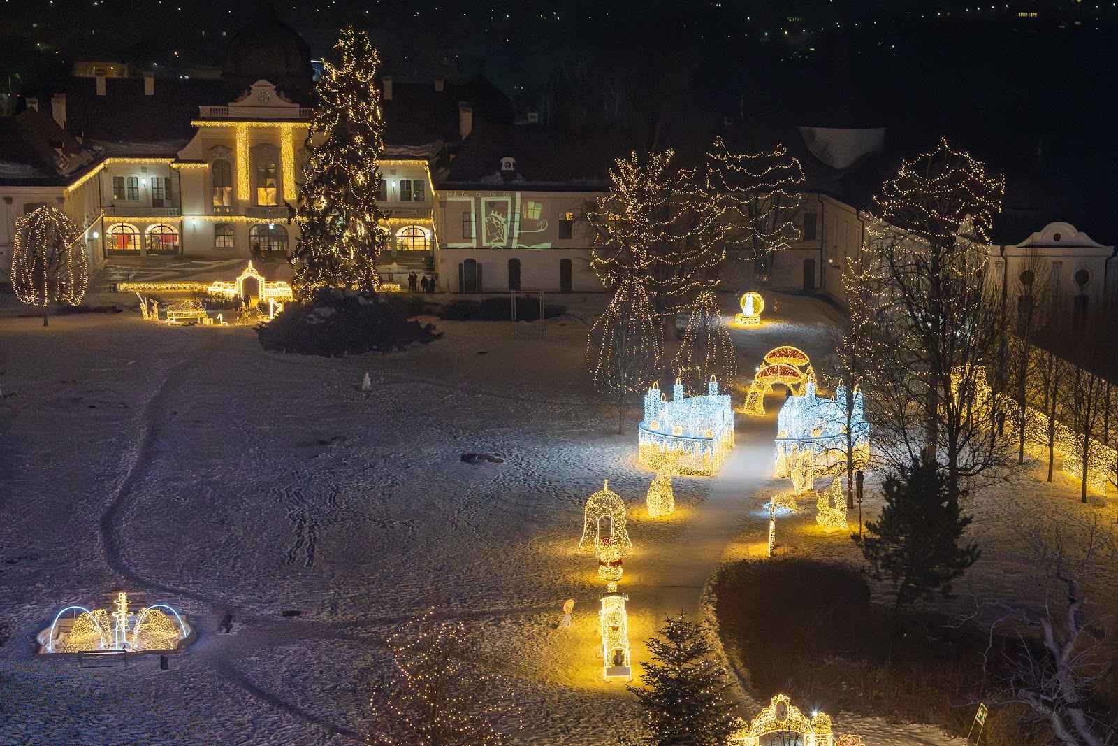 An elevated view over the whole light park, rows of illuminated sculptures across a snow-covered garden